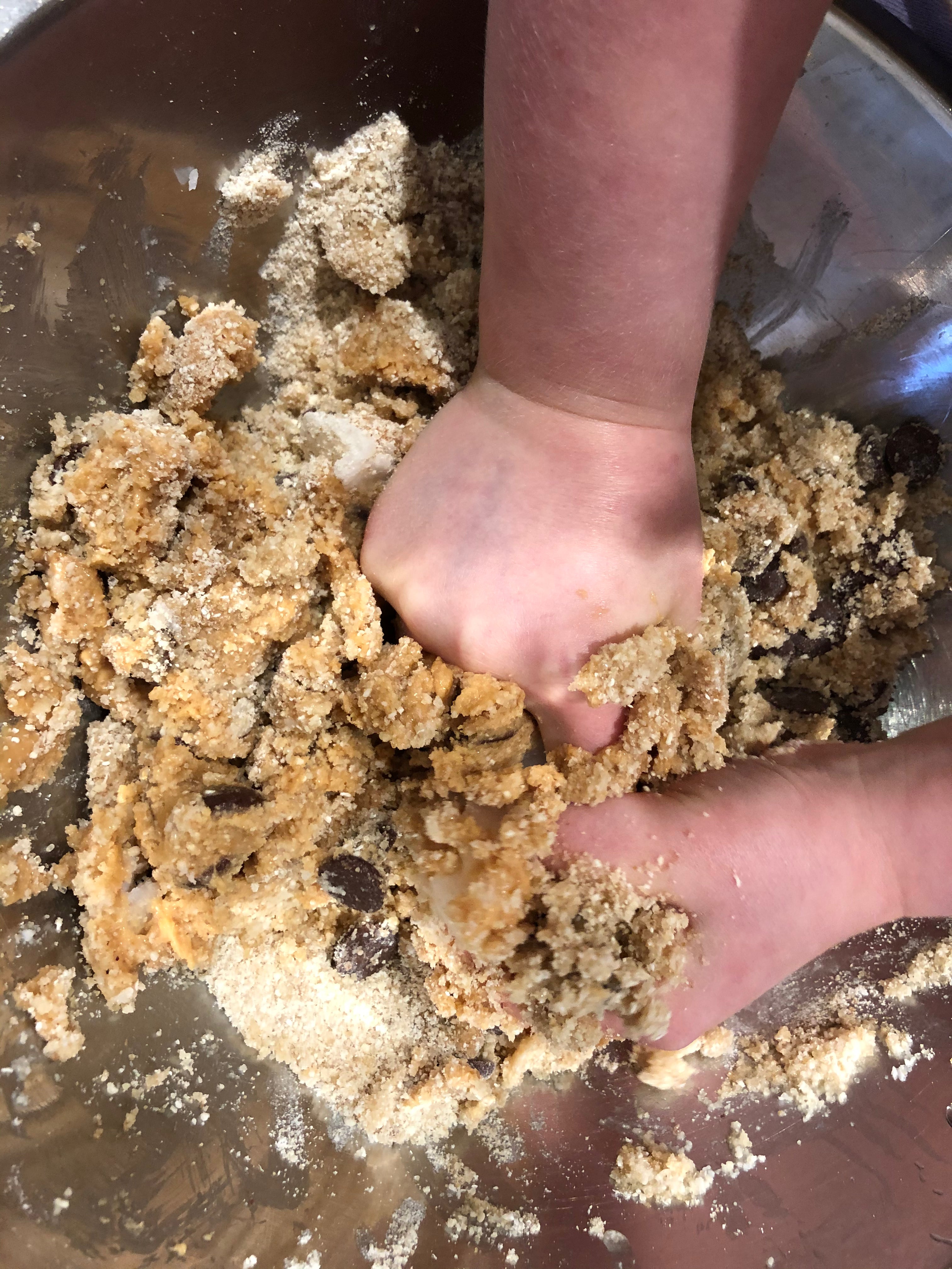 Child's hands mixing choc chip cookie dough, gluten free baking with kids, best gluten free choc chip cookies, YOMO gluten free choc chip mix in action