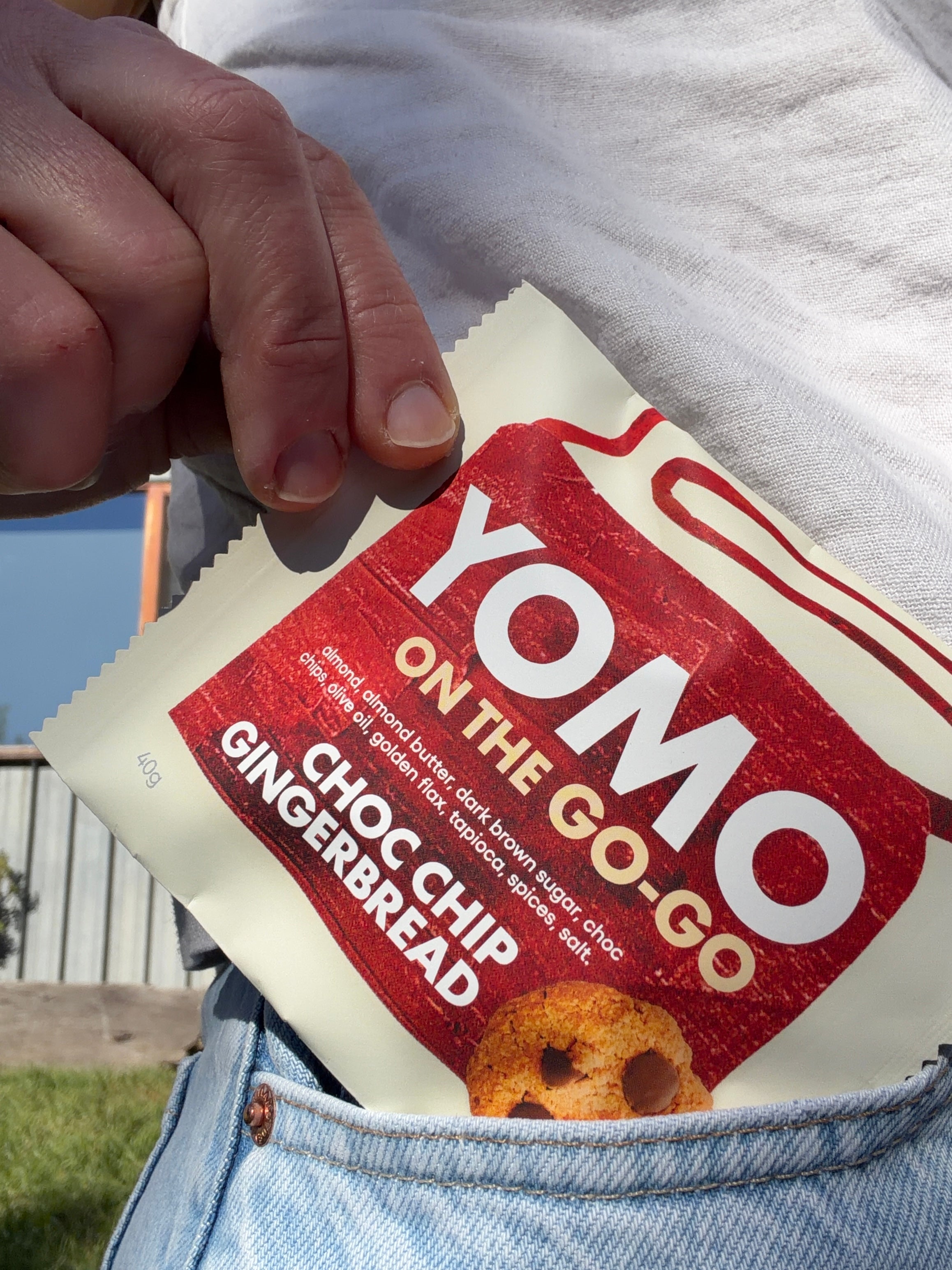 YOMO gluten free Choc Chip Gingerbread cookie package can fit in your pocket - cookie pictured going into a skirt pocket