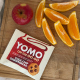 YOMO gluten free cookie on the go-go gingerbread, pictured for afternoon tea with orange slices and an apple on a wooden cutting board.