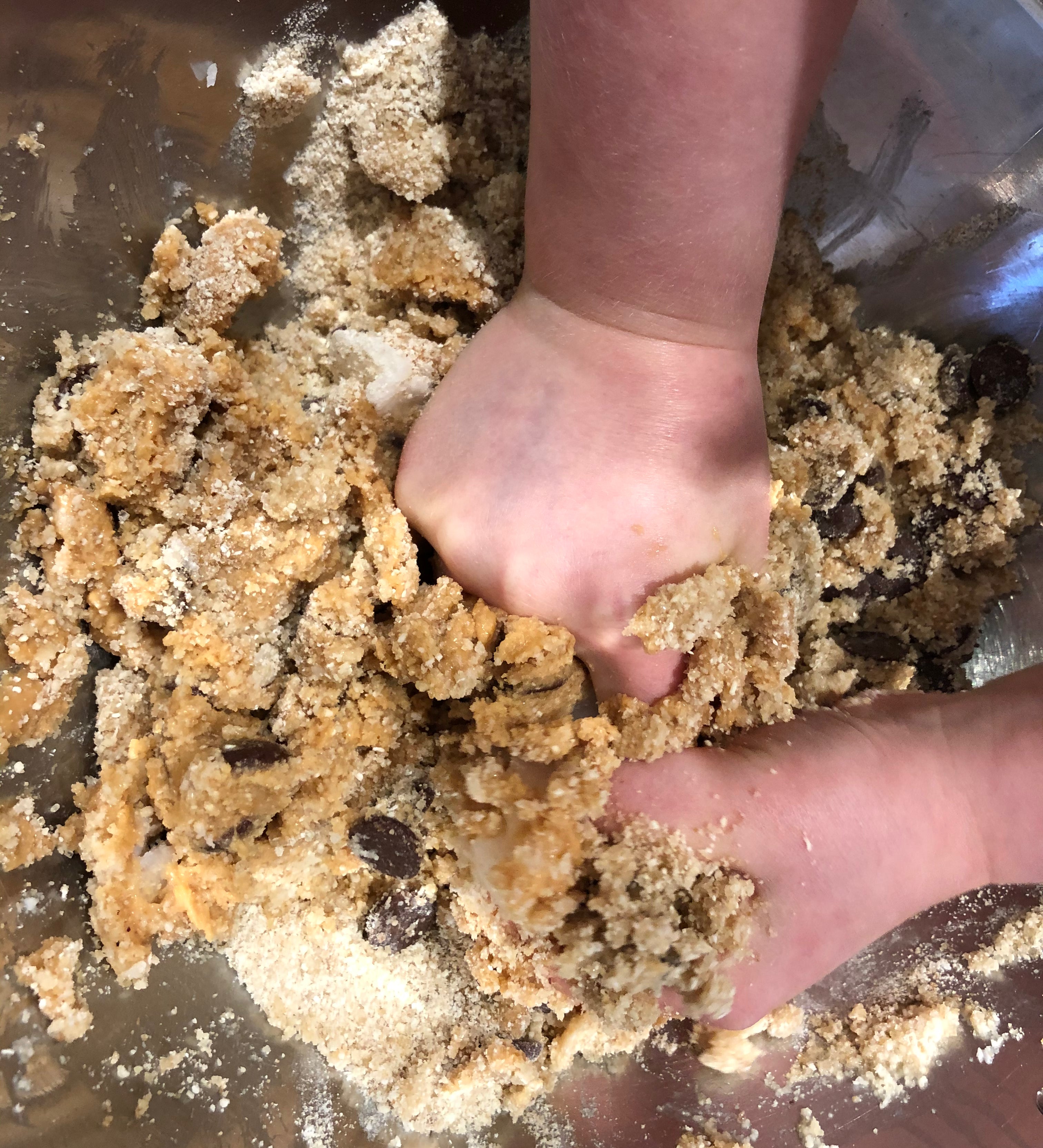 Child's hands mixing choc chip cookie dough, gluten free baking with kids, best gluten free choc chip cookies, YOMO gluten free choc chip mix in action